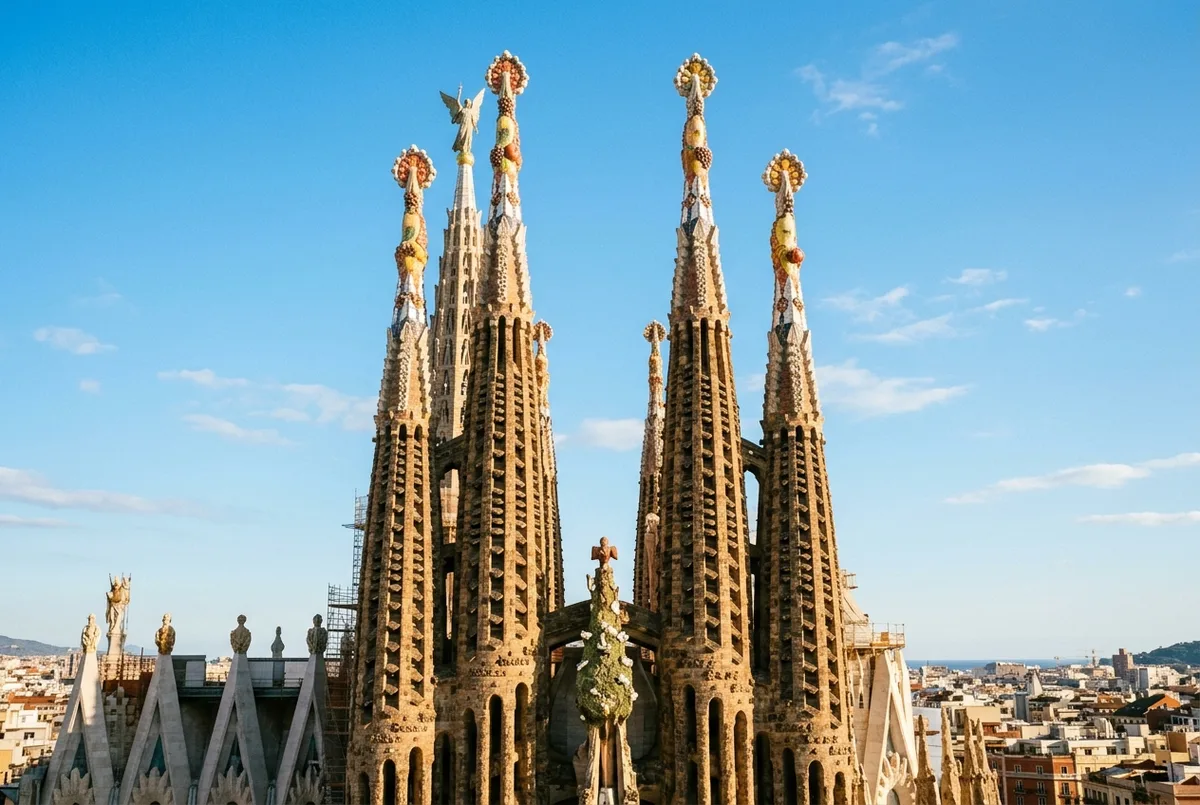 Wide shot of the sagrada familia tower meanings spires against a clear sky, showing the fruit shaped finials and carved details near the top of an apostle tower